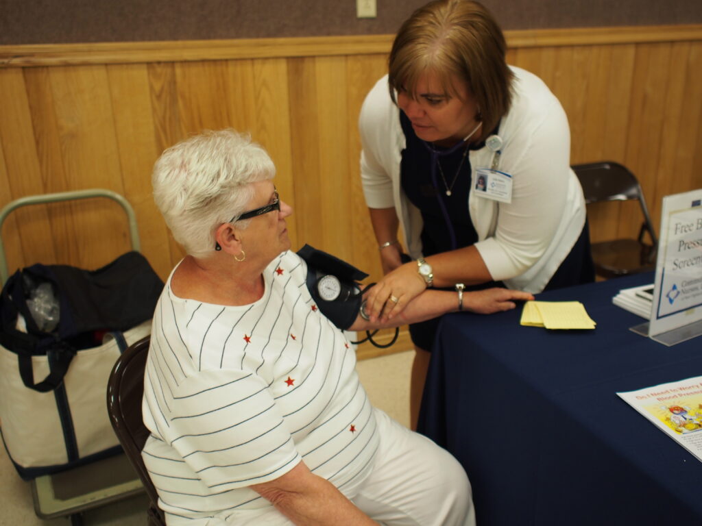 A Woman Sitting At A Chair With A Nurse Getting Blood Pressure